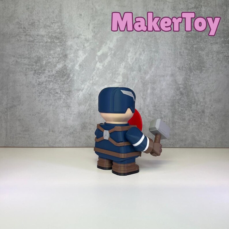 May include: A Captain America figurine, viewed from the back, holding a hammer and shield. The figurine is primarily blue, brown, and red, with a white and silver hammer. The MakerToy logo is in pink.