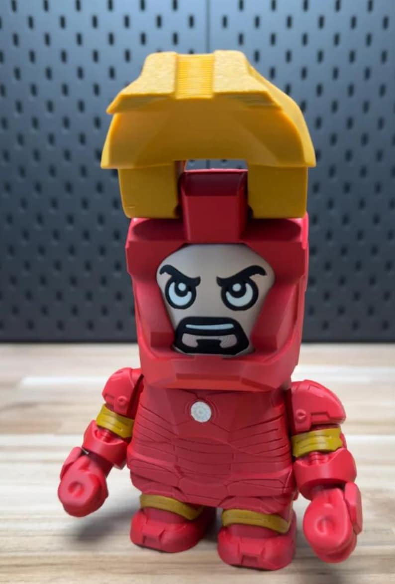 K&ouml;nnte beinhalten: Eine rot-gelbe Iron Man-Figur mit einem blockartigen Design. Die Figur hat einen Helm mit einem Gesicht und eine gelbe Struktur oben. Sie hat einen wei&szlig;en Kreis auf der Brust und gelbe Akzente an Armen und Beinen.