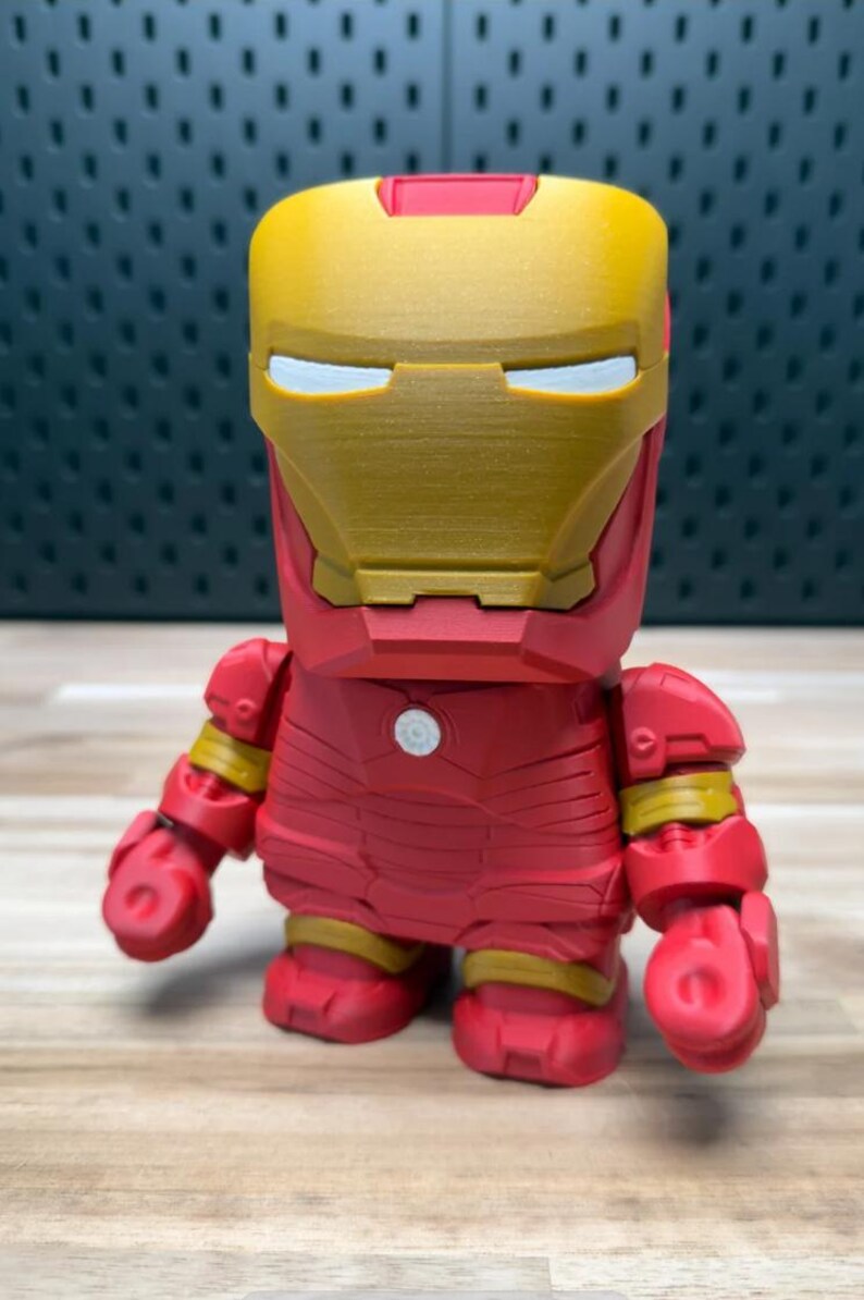 K&ouml;nnte beinhalten: Eine rot-goldene Iron Man-Figur. Die Figur hat ein blockartiges Design mit einem goldenen Helm und roter R&uuml;stung. Die Figur hat einen kleinen wei&szlig;en Kreis auf der Brust und gelbe Akzente an den Gelenken.