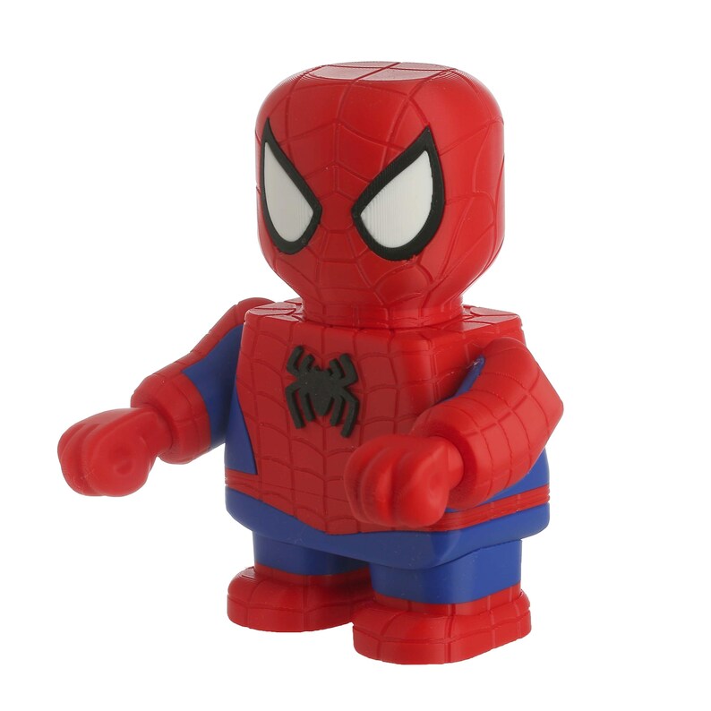 May include: A red and blue Spider-Man figurine with a blocky design. The figure has white eyes, a black spider emblem on the chest, and blue accents on the arms and legs. The figure is standing with arms outstretched.