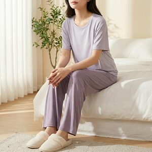 May include: A light purple short-sleeved t-shirt and matching long pants lounge set. The top features a round neckline and short sleeves, while the pants have a straight-leg cut. The set is made of a solid-colored, smooth fabric in a soft lavender hue.