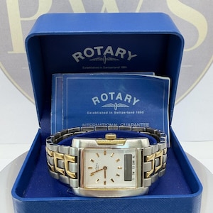 May include: A silver and gold Rotary watch with a rectangular face, presented in a blue box. The watch features a white dial with black hands and markers. The watch strap is a mix of silver and gold links. The box displays the Rotary logo and text.