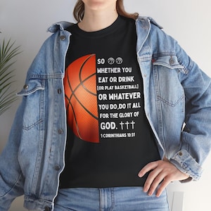 Puede incluir: Camiseta negra con un gráfico de baloncesto y el texto "SO WHETHER YOU EAT OR DRINK [OR PLAY BASKETBALL] OR WHATEVER YOU DO, DO IT ALL FOR THE GLORY OF GOD. 1 CORINTHIANS 10:31". La camiseta se lleva con una chaqueta vaquera.