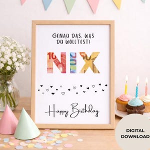 May include: A framed print with the German text "GENAU DAS, WAS DU WOLLTEST!" and "NIX" in colorful money-themed letters. Below, it reads "Happy Birthday" with heart accents. The scene includes cupcakes, party hats, and a banner.