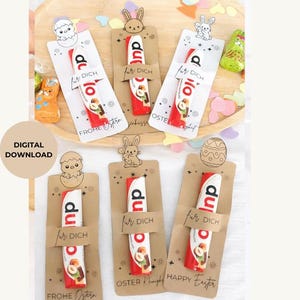 May include: A collection of Easter-themed chocolate bars with decorative toppers. Each bar is wrapped in red and white packaging and held by a brown card with the words "fur dich" and "Frohe Ostern". The toppers feature Easter bunnies and chicks.