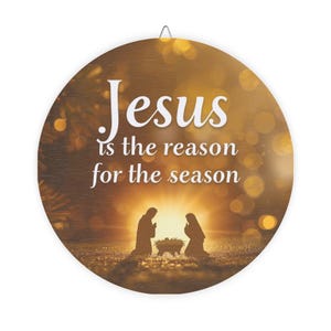 May include: Round wooden Christmas ornament with the text "Jesus is the reason for the season." The ornament features a silhouette of the nativity scene with a bright light in the background. A small metal loop is at the top for hanging.
