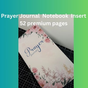 May include: A white prayer journal notebook insert with a floral design and the text "Prayer Journal" in blue lettering. The notebook has 52 premium pages.