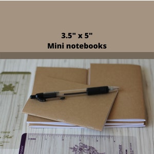 May include: A stack of three brown mini notebooks, each measuring 3.5 inches by 5 inches, with a black pen lying on top.