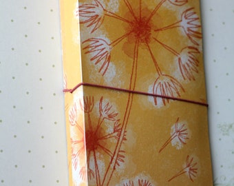 May include: A yellow journal cover with a dandelion design in white and orange. The cover has a red string tied around it and the text "DIANA M. LARSON" is printed on the bottom.