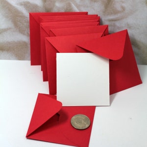 May include: A stack of red square envelopes with a white card and a silver coin on top of a red envelope.