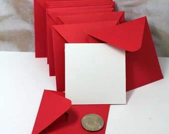 May include: A stack of red square envelopes with a white card and a silver coin on top of a red envelope.