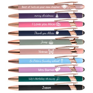 Op de afbeelding: Een verzameling van tien gepersonaliseerde pennen in verschillende kleuren, waaronder roze, blauw en groen, met roségouden accenten. Elke pen heeft een andere inscriptie, zoals "Best of luck on your new chapter" en "I Love you Alice."