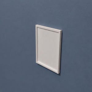 Puede incluir: Un marco de fotos rectangular de color blanco con un borde de líneas limpias y un panel interior blanco sólido. El marco está montado plano contra una pared azul mate sólida, mostrando un diseño simple y uniforme sin elementos decorativos.