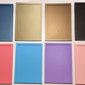 Puede incluir: Ocho marcos rectangulares dispuestos en dos filas de cuatro. La fila superior presenta marcos azul, dorado, bronce y negro. La fila inferior muestra marcos rosa, azul claro, morado y rosa claro. Cada marco tiene una superficie plana y lisa.