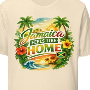 May include: Cream-colored t-shirt featuring a colorful graphic with the text "Jamaica Feels Like Home." The design includes palm trees, a sunset, flowers, and the Jamaican flag. The shirt is a short-sleeved crew neck.