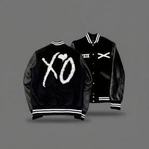 May include: Black varsity jacket with white accents and leather sleeves. The jacket features the text "XO" on the back and "XIV" and an "X" on the front. The jacket has a striped collar, cuffs, and hem.