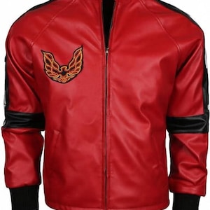 Puede incluir: Chaqueta de cuero roja con cuello, puños y rayas negras en las mangas. La chaqueta tiene una cremallera completa y un parche con un emblema de pájaro en el pecho. Cuello alto.
