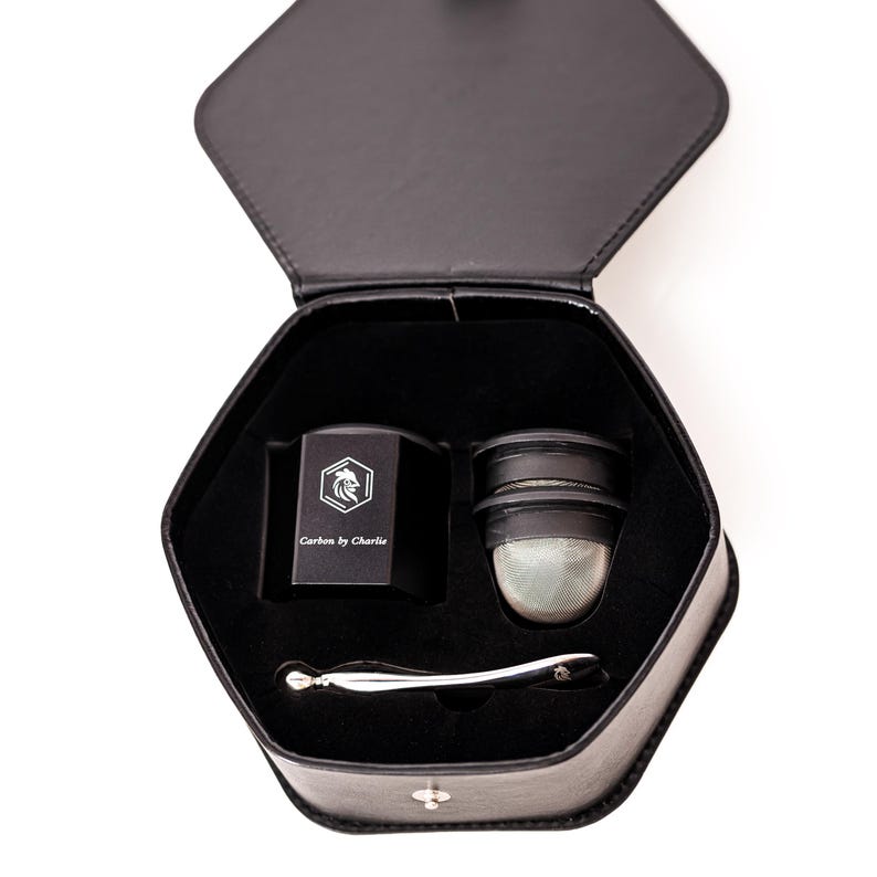 Black Carbon by Charlie grinder set displayed inside a hexagon storage case with a mesh insert and metal tool.