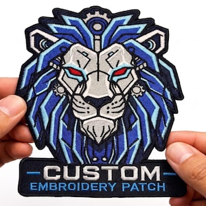 May include: An embroidered patch featuring a stylised mechanical lion head with blue, silver, and black thread, accented by glowing red eyes and gear details. Below the lion, a rectangular black banner displays the white text CUSTOM EMBROIDERY PATCH.