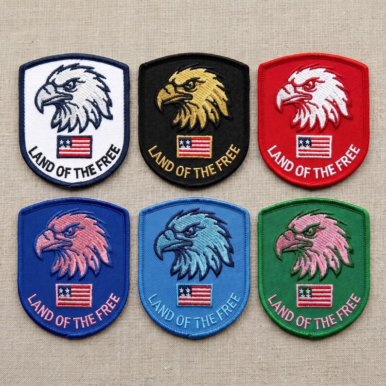 May include: Six embroidered patches with an eagle design and the text "LAND OF THE FREE". The patches are in various colors, including white, black, red, blue, and green, with the eagle in different colors as well. Each patch features a small American flag.