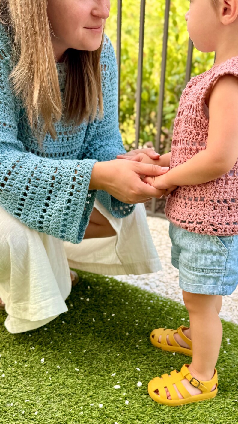 Op de afbeelding: Een lichtblauw gehaakt shirt met lange mouwen en een grof breipatroon, gecombineerd met een witte broek. Een mouwloos oudroze gehaakt shirt met een bijpassend grof patroon, lichtblauwe spijkerbroek en mosterdgele rubberen sandalen met gespen.