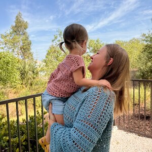 May include: A dusty rose crochet top with short sleeves and a blue long-sleeved crochet jumper. The crochet garments feature a repeating openwork stitch pattern throughout the fabric, showcasing the intricate texture of the handmade yarn construction.