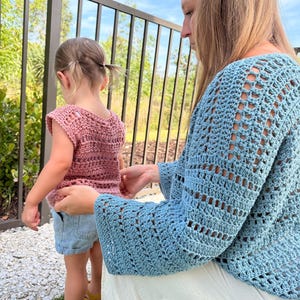 Puede incluir: Un top de ganchillo color rosa empolvado de manga corta con patr&oacute;n texturizado, combinado con pantalones cortos de mezclilla azul claro y sandalias amarillas. Un su&eacute;ter de ganchillo azul claro de manga larga con dise&ntilde;o calado sobre falda blanca.