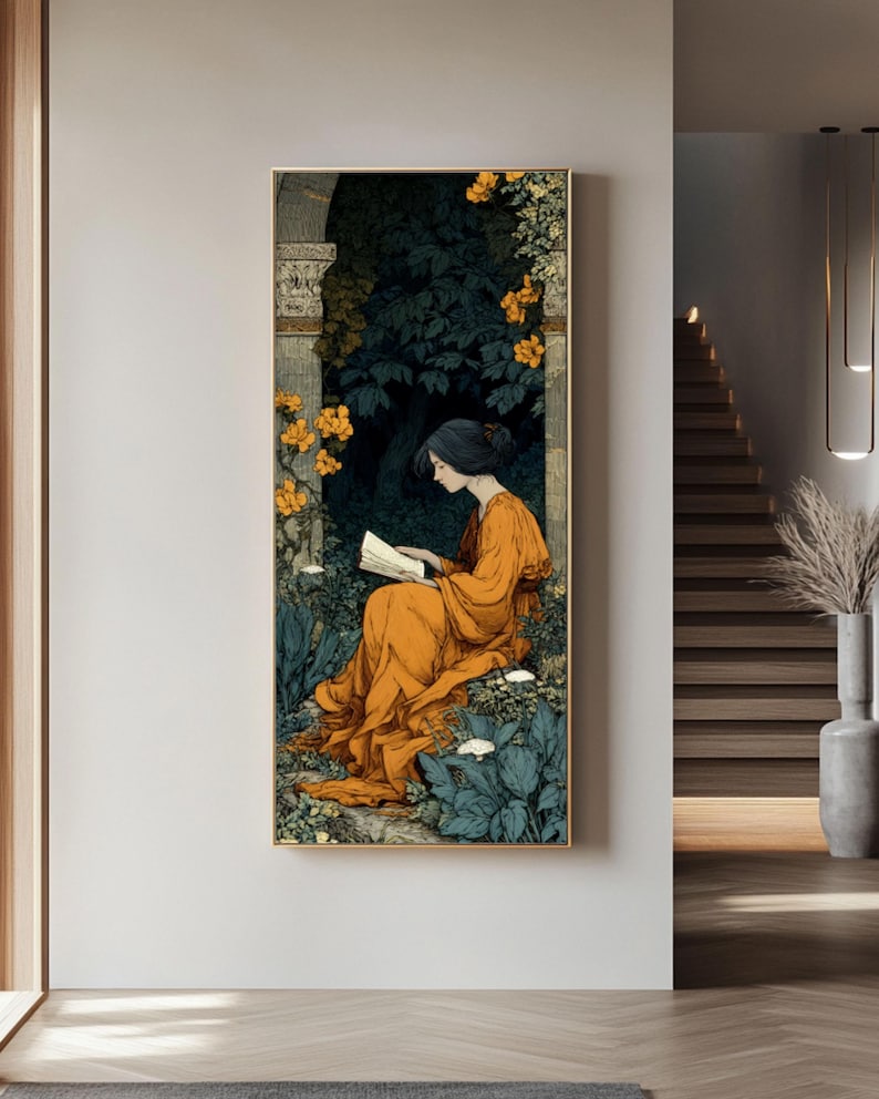 May include: A vertical framed wall art print depicting a person with dark hair wearing a long orange dress, sitting and reading a book within a stone archway surrounded by dark green foliage, blue-tinted plants, and clusters of bright yellow flowers.