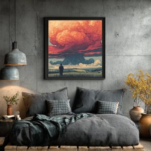 Pode incluir: Uma impressão de arte emoldurada retrata uma paisagem dramática com uma grande formação de nuvens vermelhas e laranja sobre um campo. Uma figura solitária está em primeiro plano. A obra de arte está pendurada acima de uma cama com roupa de cama cinza e almofadas decorativas.