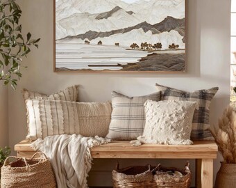 May include: A cozy living room scene featuring a wooden bench adorned with various textured pillows and a fringed throw. A large framed artwork depicts a mountain landscape. Woven baskets and a jute rug complete the warm, inviting decor.