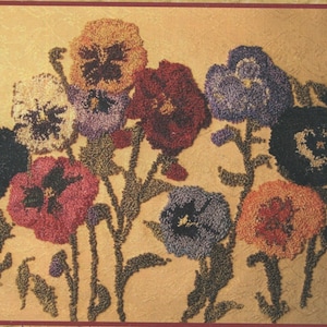 May include: A punch needle embroidery kit titled "Pansy Patch" by French Fantasy Designs. The design features colorful pansies in shades of orange, red, purple, and blue. The finished size is 8" x 10".