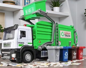 May include: A green and white toy garbage truck with the words "POWER" and "RESCUE FORCE" printed on the cab. The truck has a lifting arm and a green trash bin. Several small trash bins in various colors are in front of the truck.
