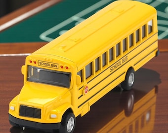 Puede incluir: Un autobús escolar de juguete amarillo brillante con detalles en negro y las palabras "SCHOOL BUS" impresas en el lateral. El autobús tiene neumáticos negros y una señal de stop. La parte delantera del autobús tiene una parrilla y faros negros.