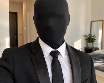 May include: A black full-head spandex mask worn with a crisp white collared dress shirt, a solid black necktie, and a black suit jacket featuring satin lapels. The mask covers the entire face and head, creating a smooth, featureless appearance.