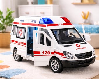 May include: A white toy ambulance with red and blue lights on top. The toy has the number "120" on the side and front, and the word "AMBULANCE" is printed on the front. The doors are open, revealing the interior.