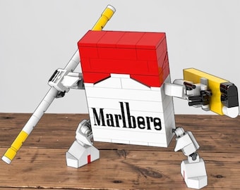 May include: A creative Lego model of a Marlboro cigarette pack transformed into a robot. The robot features a red top, white body with "Marlboro" text, and yellow and white arms and legs. The model is set on a wooden surface.