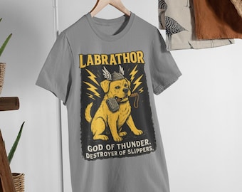 May include: A gray t-shirt featuring a cartoon Labrador Retriever with a helmet and hammer, labeled "LABRATHOR, GOD OF THUNDER. DESTROYER OF SLIPPERS." The design includes yellow lightning bolts and a black background.