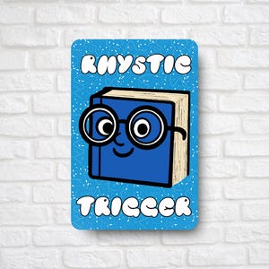 May include: A blue rectangular sign with the words "RHYSTIC TRIGGER" and a cartoon book wearing glasses. The book has a smiling face and is blue with tan pages. The background is light blue with white dots.