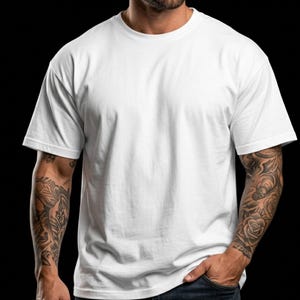 May include: A plain white, short-sleeved t-shirt. The shirt is made of a soft material and has a crew neck. The person wearing the shirt has tattoos on both arms. The background is black.