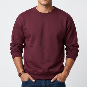 Puede incluir: Una sudadera de color granate liso con cuello redondo, mangas largas con pu&ntilde;os acanalados y dobladillo acanalado. La prenda presenta un dise&ntilde;o sencillo y liso con un escote redondeado, confeccionada en un tejido suave y opaco.