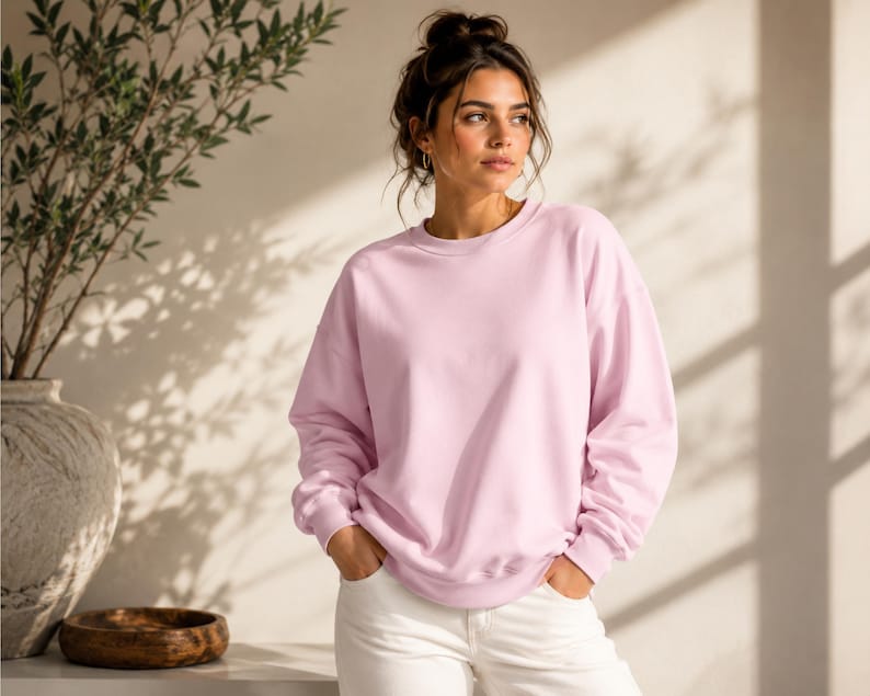 Puede incluir: Una sudadera de cuello redondo en color rosa claro con mangas largas y pu&ntilde;os acanalados, combinada con pantalones blancos. La sudadera presenta un corte relajado, un escote redondo sencillo y un color pastel s&oacute;lido y uniforme.