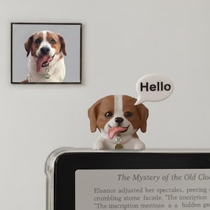 May include: A brown and white dog figurine with its tongue sticking out, and a speech bubble that says "Hello". A framed picture of a similar dog is in the background.