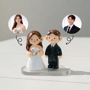 Pode incluir: Um topo de bolo de casamento com figuras de noiva e noivo. A noiva usa um vestido branco e segura um buquê. O noivo está de terno preto. O topo fica em uma base transparente.
