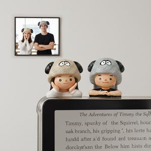 Puede incluir: Dos figuras de personas con sombreros de oveja, con una foto enmarcada de dos personas con los mismos sombreros en el fondo. Las figuras están encima de una tableta con el texto "The Adventures of Timmy the Sql".