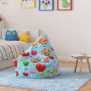 Puede incluir: Un puf azul con un estampado de piruletas de colores. Las piruletas son de varias formas y colores, incluyendo corazones rojos, espirales amarillas y círculos verdes. La silla está sobre una alfombra azul claro en un dormitorio infantil.