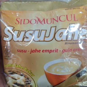 以下が含まれることがあります： SidoMuncul Susu Jaheのパッケージ。生姜ミルクドリンクです。パッケージは金色とオレンジ色で、インドネシア語のテキストが入っています。画像には、飲み物のカップと生姜の写真が写っています。27グラム入りです。