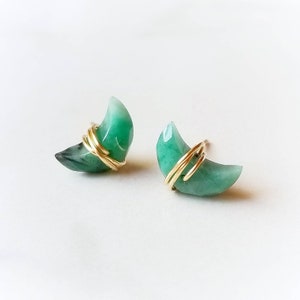 May include: A pair of crescent moon shaped earrings made with green gemstone and gold wire.
