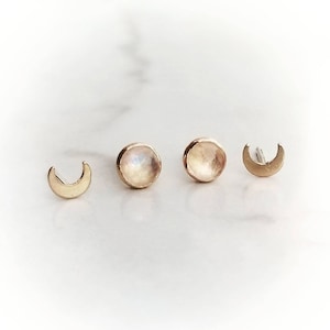 May include: A set of three gold earrings featuring two moonstone studs and a crescent moon charm.