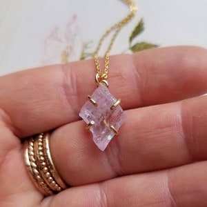Pu&ograve; includere: Una delicata collana a catena dorata con un ciondolo di cristallo rosa. Il cristallo &egrave; sfaccettato e ha una leggera qualit&agrave; iridescente. Il ciondolo &egrave; incastonato in una ghiera dorata.