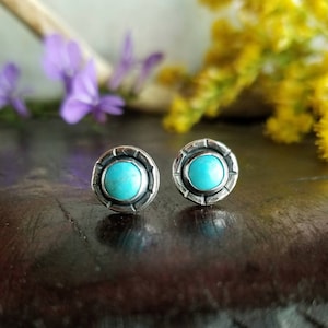 Puede incluir: Un par de pendientes de plata con piedras turquesa engastadas en un diseño circular.